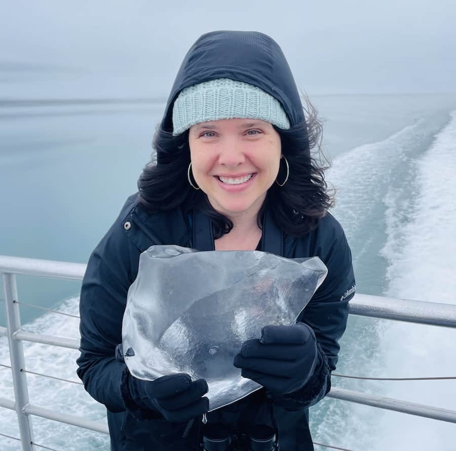 Heather smiling and holding a large piece of glacier ice
