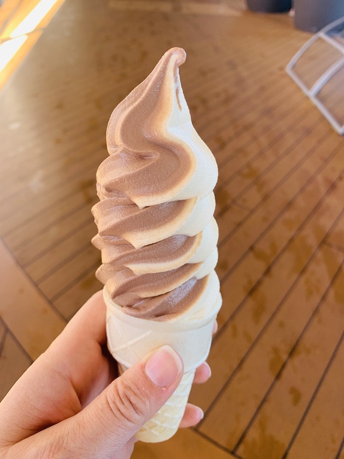 hand holding a chocolate and vanilla swirl soft serve ice cream in a gluten-free cone