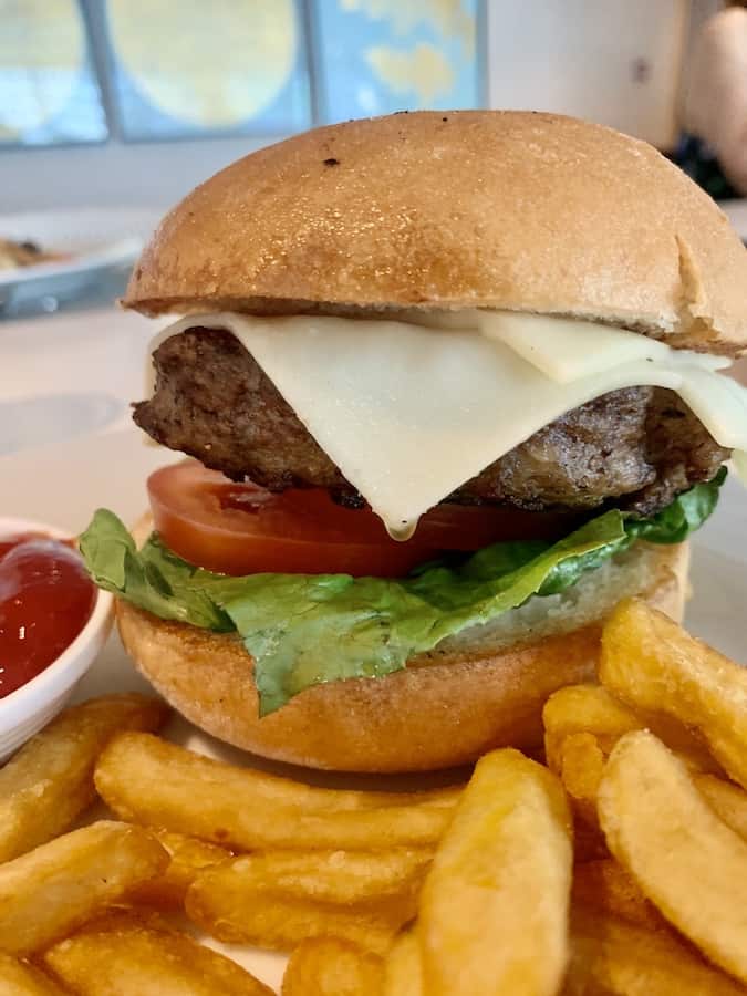 cheeseburger on a gluten-free bun with white cheese, tomato and lettuce, French fries and ketchup