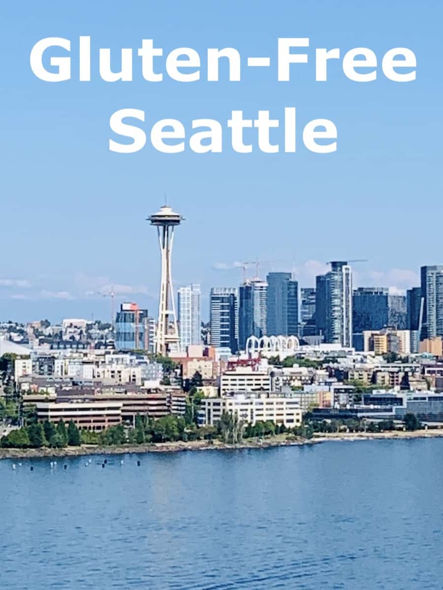 view of the Seattle skyline over the water, white text in the blue sky: Gluten-Free Seattle