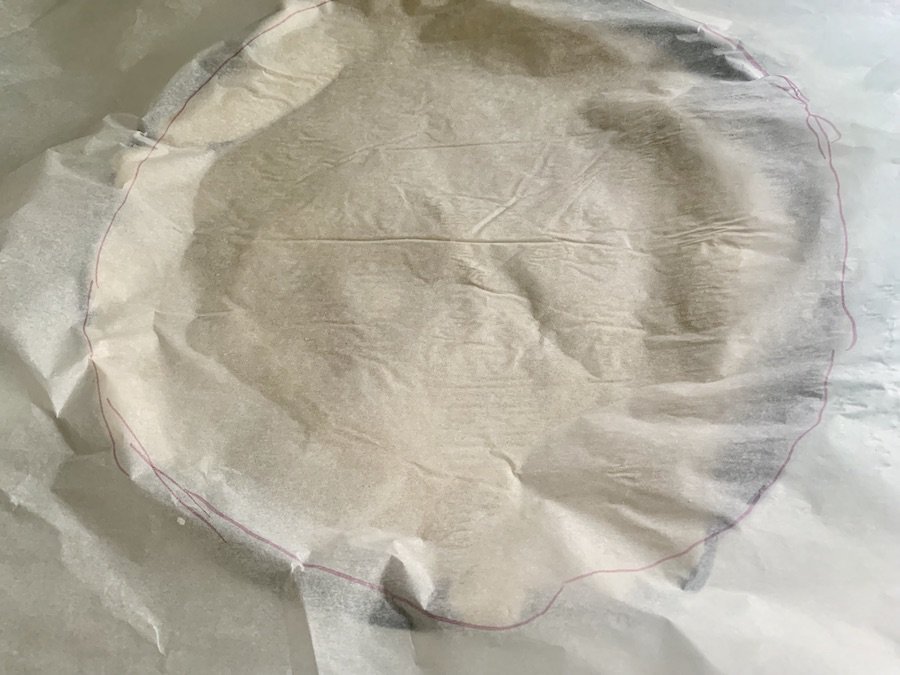 parchment paper covering a raw pie crust over a skillet