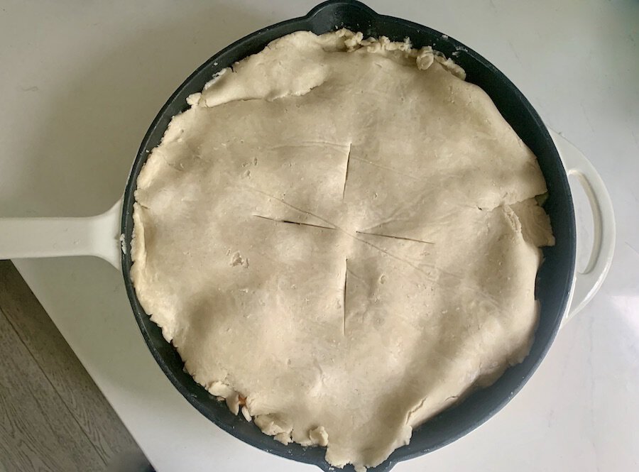 bird's eye view of dough topping a skillet with four slit marks to vent