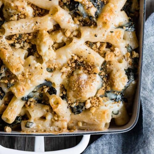Part of pan filled with creamy cauliflower baked rigatoni, topped with bread crumbs.