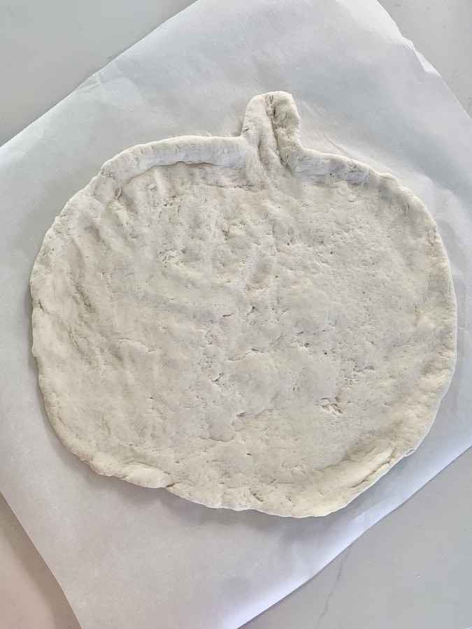 Pumpkin shaped pizza dough on parchment paper.