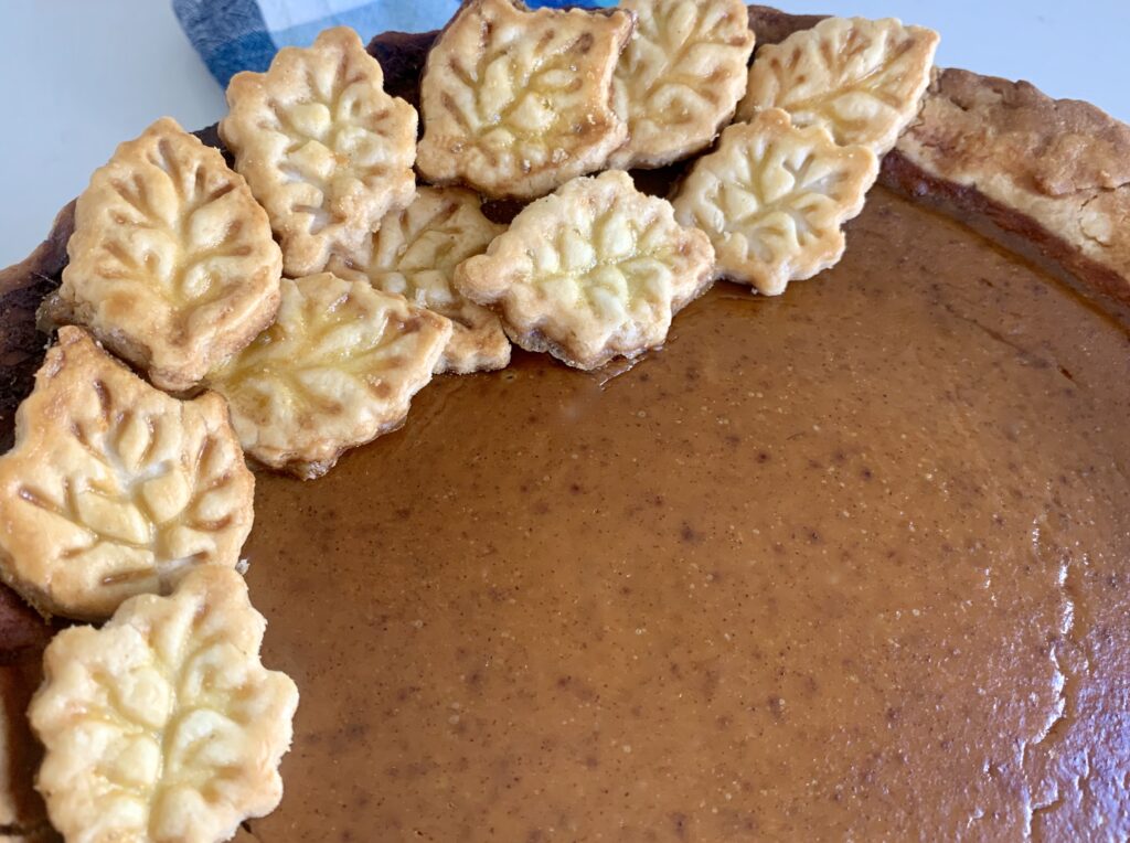 part of a pumpkin pie with pastry leaf shapes decorating the side