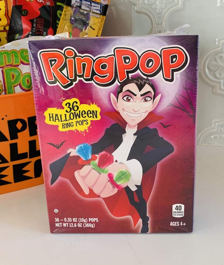 Box of Ring Pops with a vampire on the cover wearing Ring Pops. Orange bucket with Halloween candy in the background.