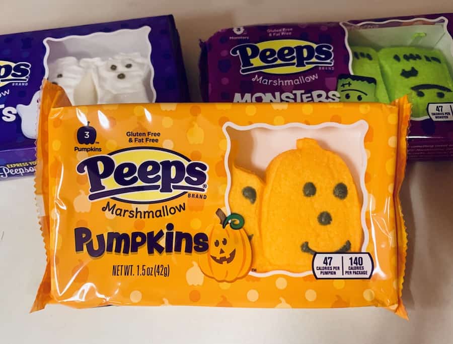 A box of pumpkin shaped Peeps. In the background are boxes of ghost peeps and Frankenstein peeps.