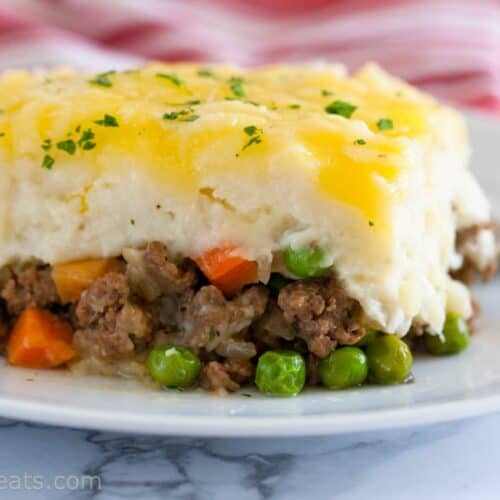 A slice/square of shepherd's pie with meat and pea/carrot filling, topped with mashed potatoes.