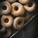 a baking sheet full of a pile of gluten-free apple cider donuts