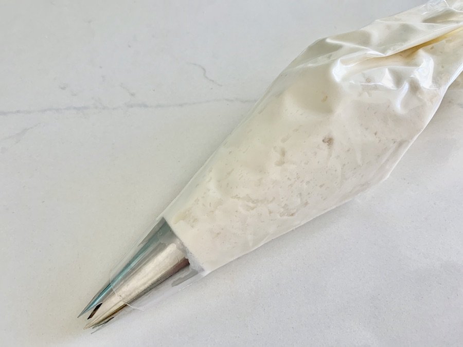 maple whipped cream in a piping bag with a star tip, resting on the counter