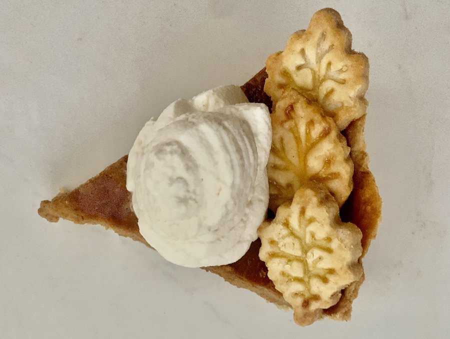 bird's eye view: slice of pumpkin pie with crust leaf decorations and a dollop of maple whipped cream