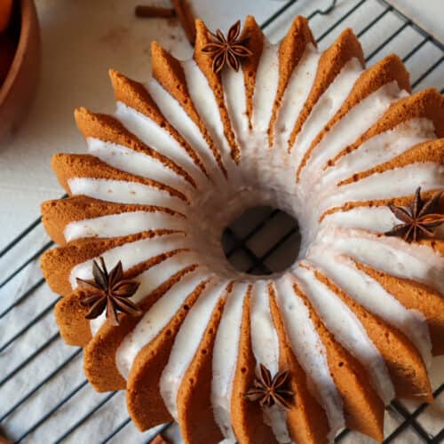 Birds' eye view of orange bundt cake with icing and spices on top.