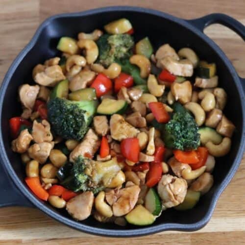 Skillet with chicken pieces and veggies.