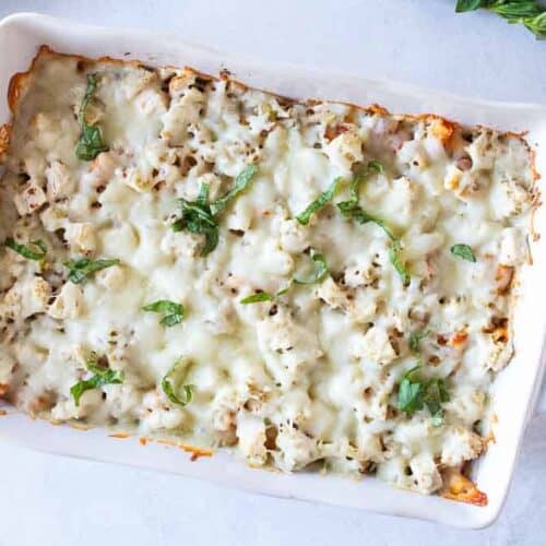 Birds eye view: white casserole dish filled with baked ziti topped with lots of melted white cheese.