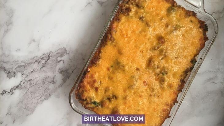 Birds eye view: glass casserole dish with chicken tamale casserole topped with melted cheddar cheese.