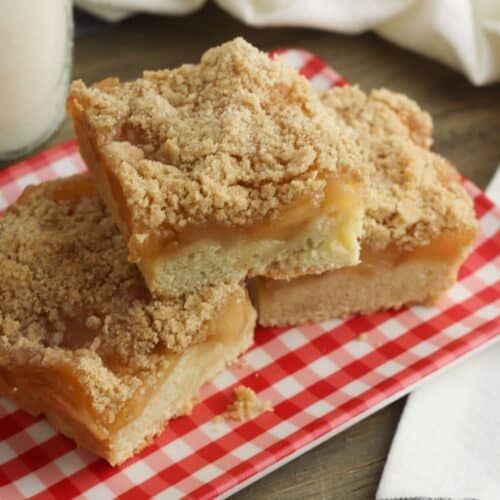 3 gluten-free apple pie bars on top of a red and white gingham napkin.