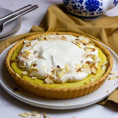 Round sweet potato tart covered with whipped cream and sprinkled with sliced almonds and cinnamon.