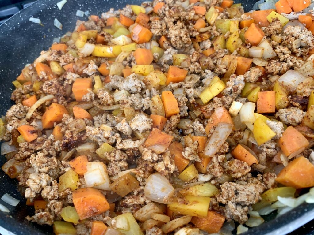Mixture of spices, turkey, and veggies in a frying pan.