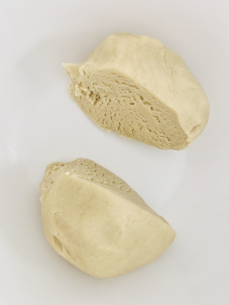 A ball of beige gluten-free dough cut into two pieces.