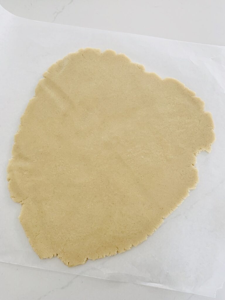 Cookie dough rolled out on top of a sheet of parchment paper