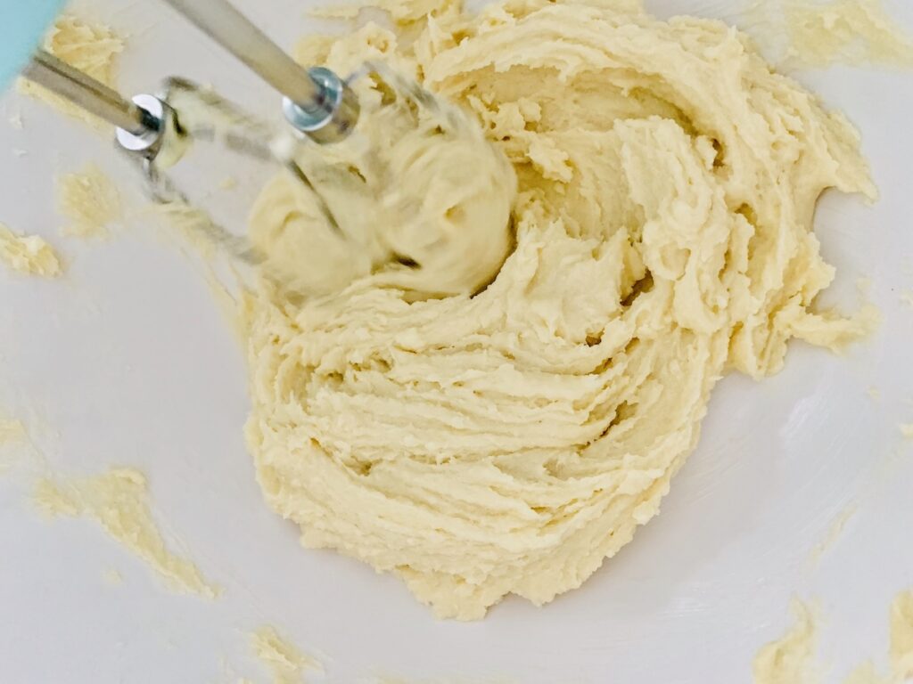 A creamy, slightly yellowish mixture with beaters spinning in the mix.