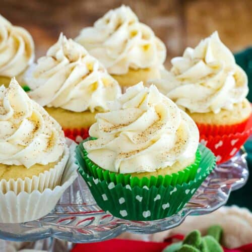 Eggnog cupcakes in colorful red and white polkadot cupcake wrappers and generously topped with eggnog frosting formed into elegant peaks.