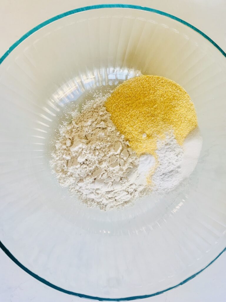 White and yellow dry ingredients in a glass bowl, unmixed.