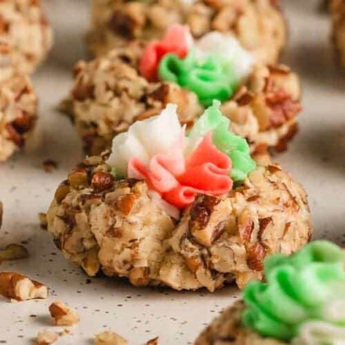Pecan covered drop cookies with red white and green buttercream frosting in the middle.