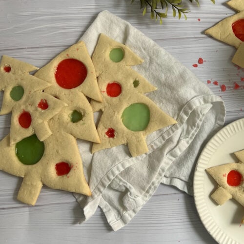 Tree-shaped sugar cookies with red & green translucent "glass/candy" filled circle cut outs throughout.
