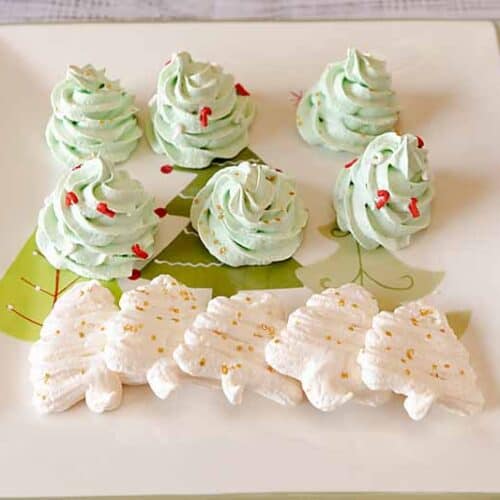 6 green tall meringue Christmas trees standing behind a row of white, flat meringue trees.