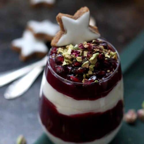 Layered red and white parfait in a glass, garnished with a star cookie.