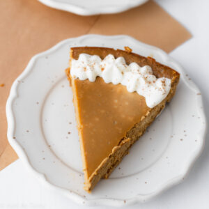 Bird's eye view: slice of brown gingerbread cheesecake trimmed with whipped cream.
