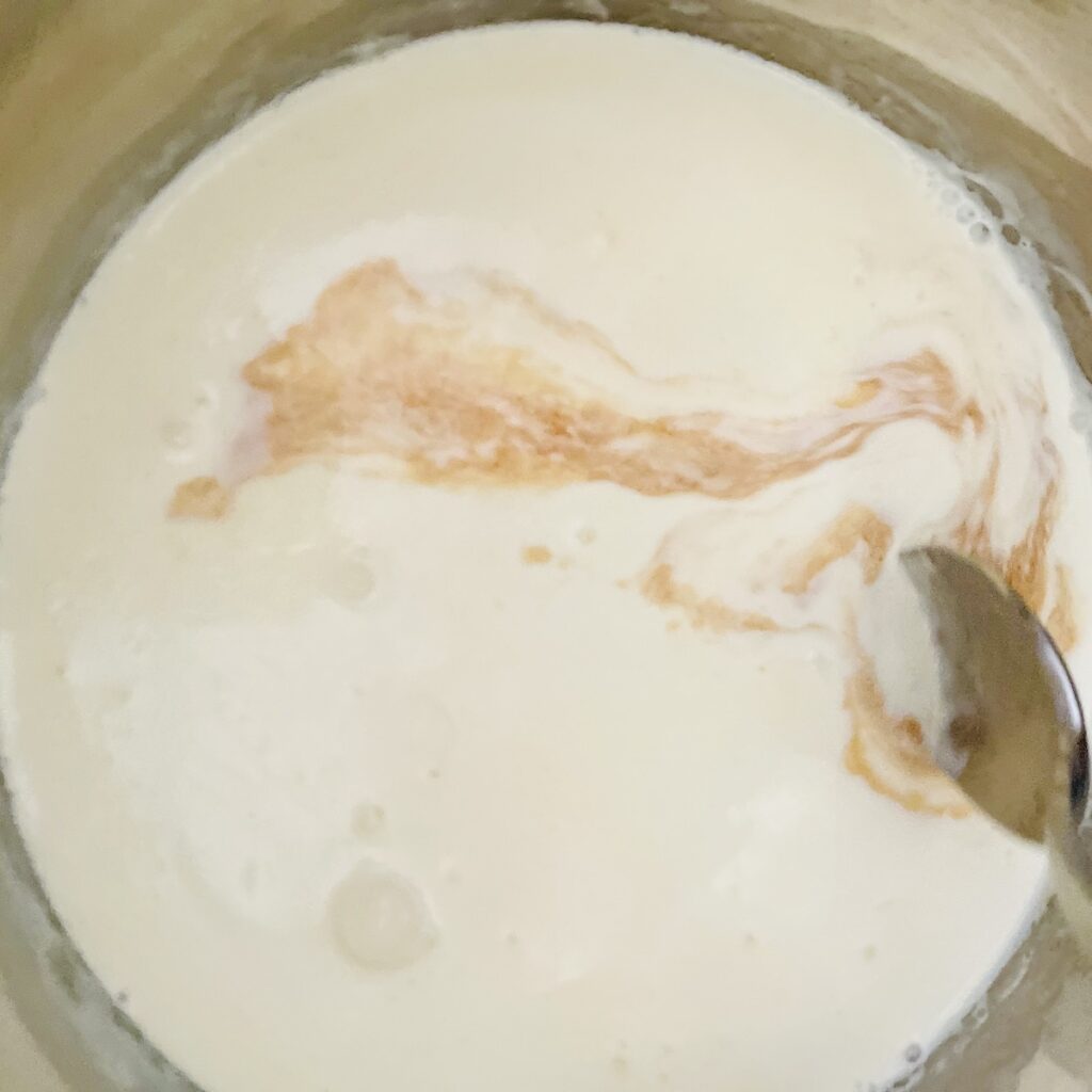 Birds eye view: spoon stirring vanilla into cream.
