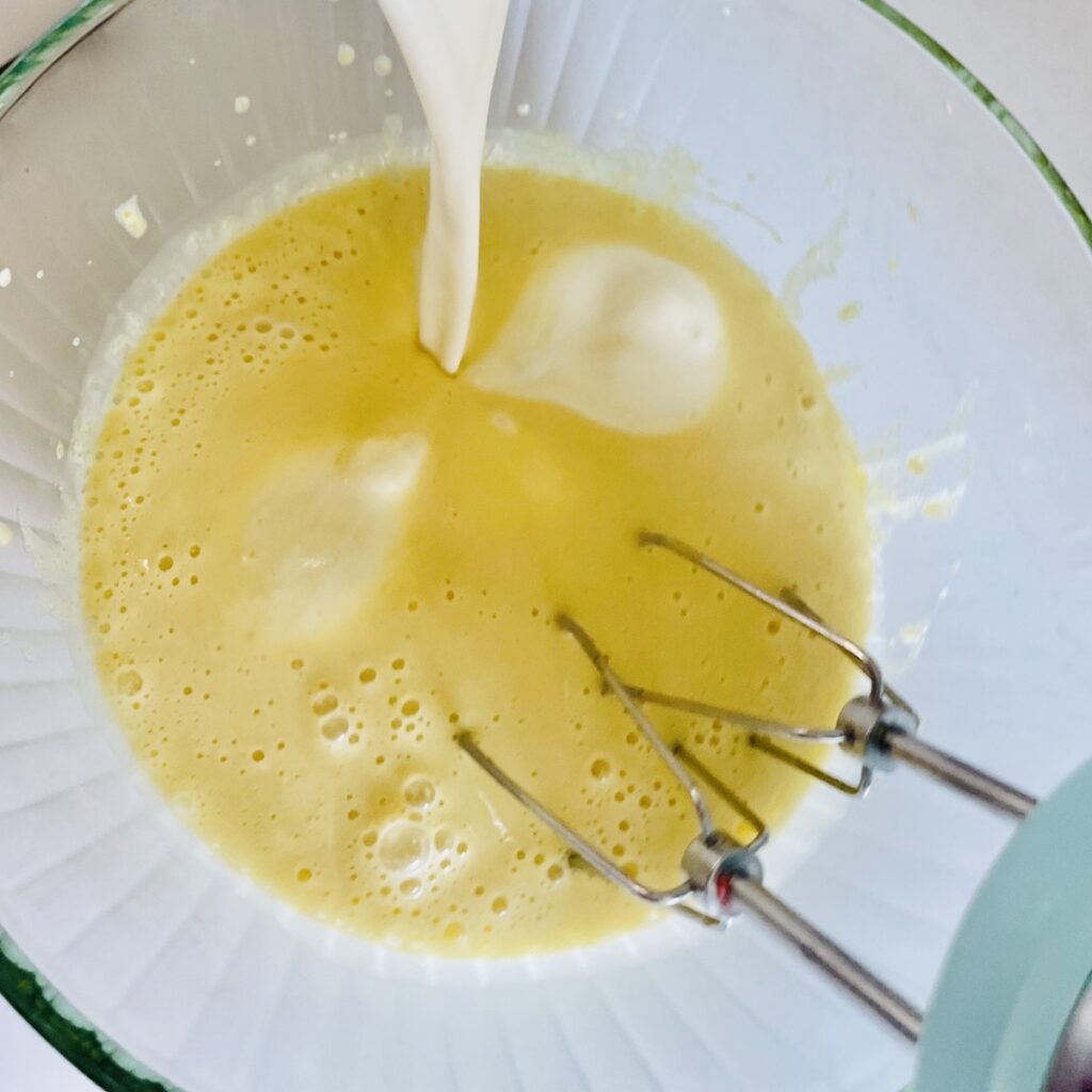 Birds eye view: cream mixture being poured into the pale yellow egg mixture.