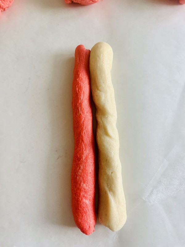 Overhead view: a strip of red dough next to white dough.