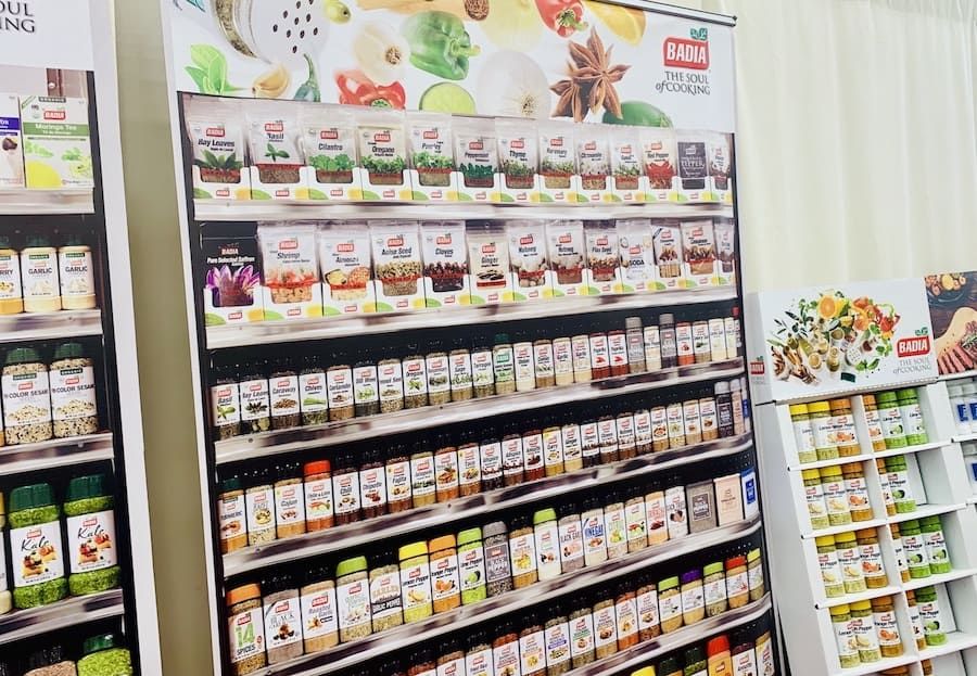 Poster displaying shelf of Badia spices surrounded by actual spice displays.