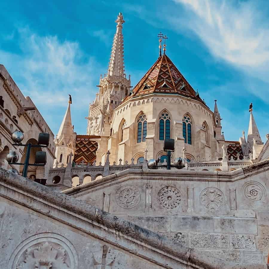 View looking up at Fisherman's Bastion Staircase and the steeple of a chapel located on top.
