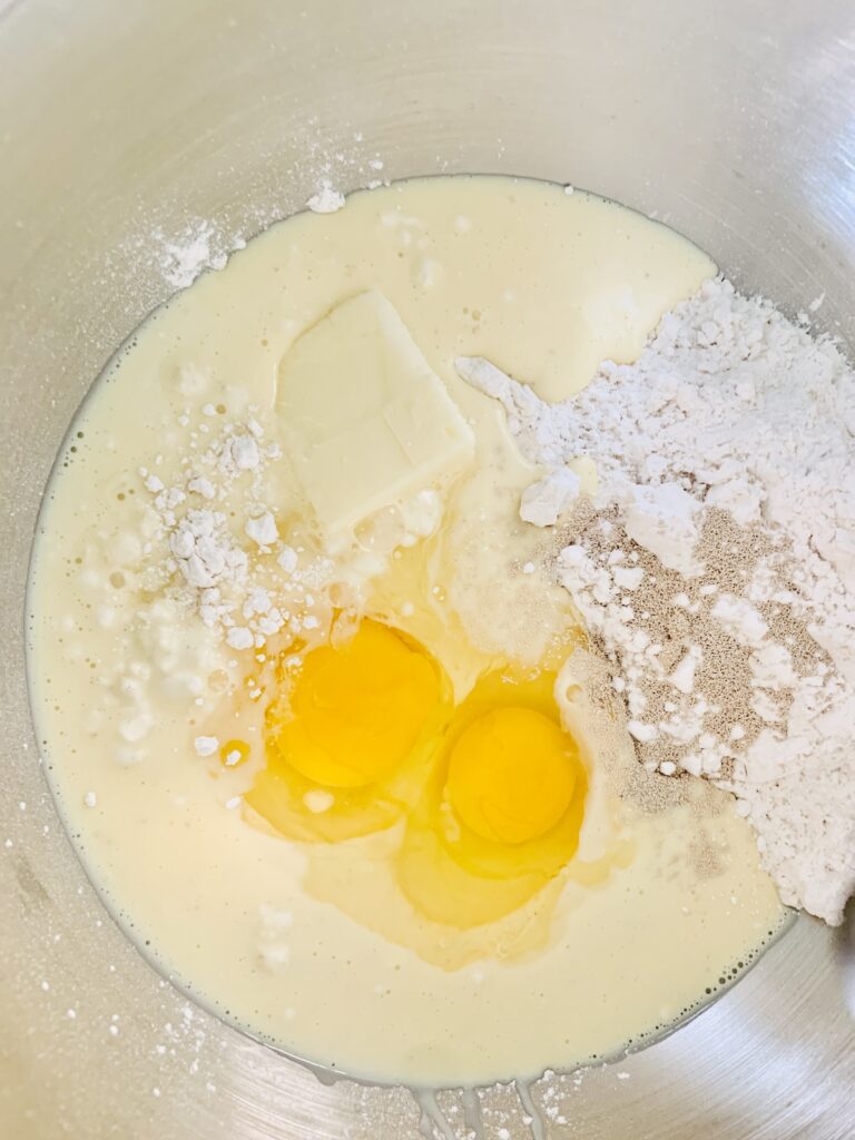 Birds Eye view: mixing bowl with flour, butter, 2 eggs, yeast, sugar & salt.
