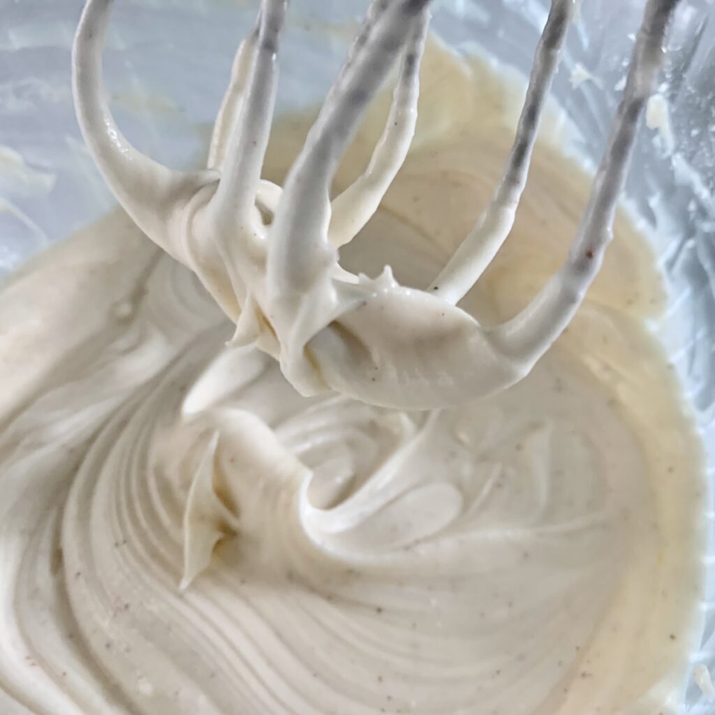 Beaters being lifted out of smooth, mixed eggnog icing.