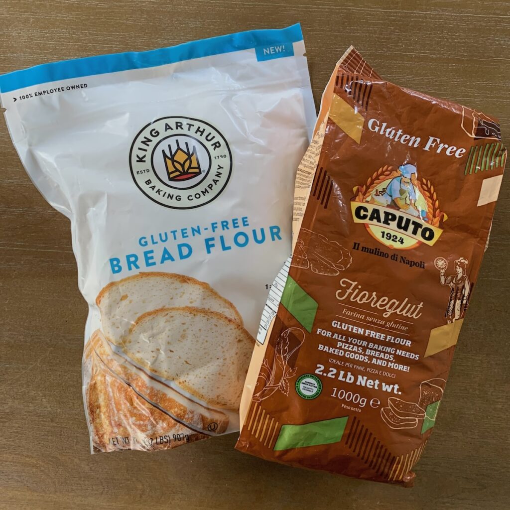 Bag of King Arthur Gluten Free Bread Flour and bag of Caputo Fioreglut Gluten Free Flour on a table.