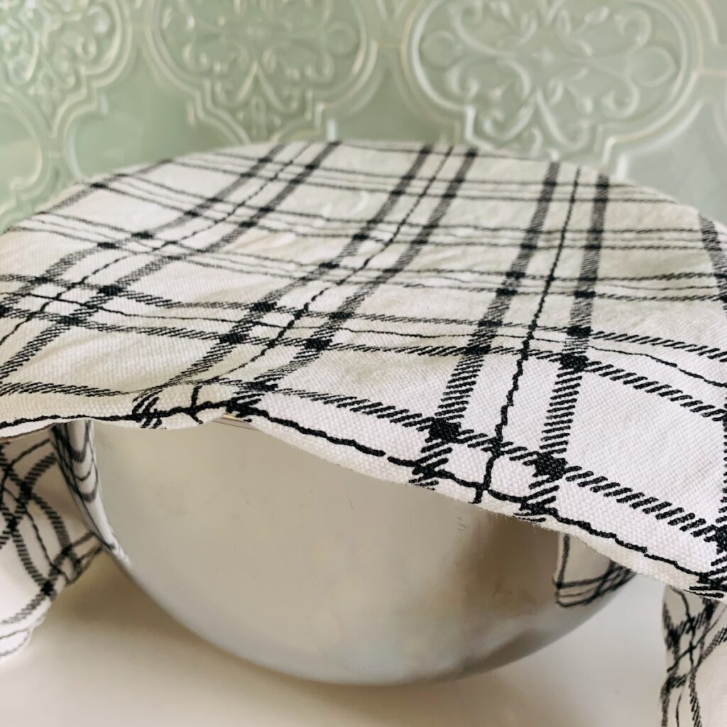 Mixing bowl covered with white and black plaid dishtowel.