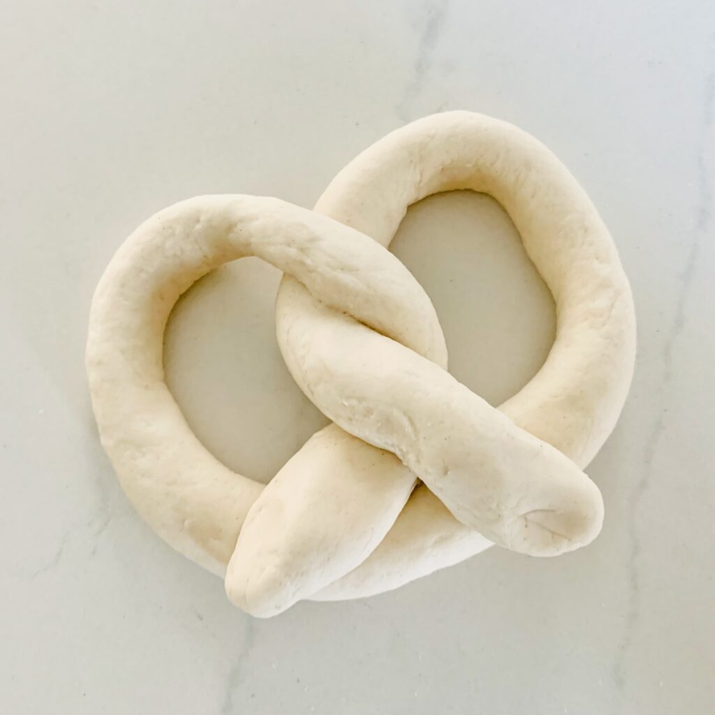 Bird's eye view: unbaked soft pretzel dough in a pretzel shape.