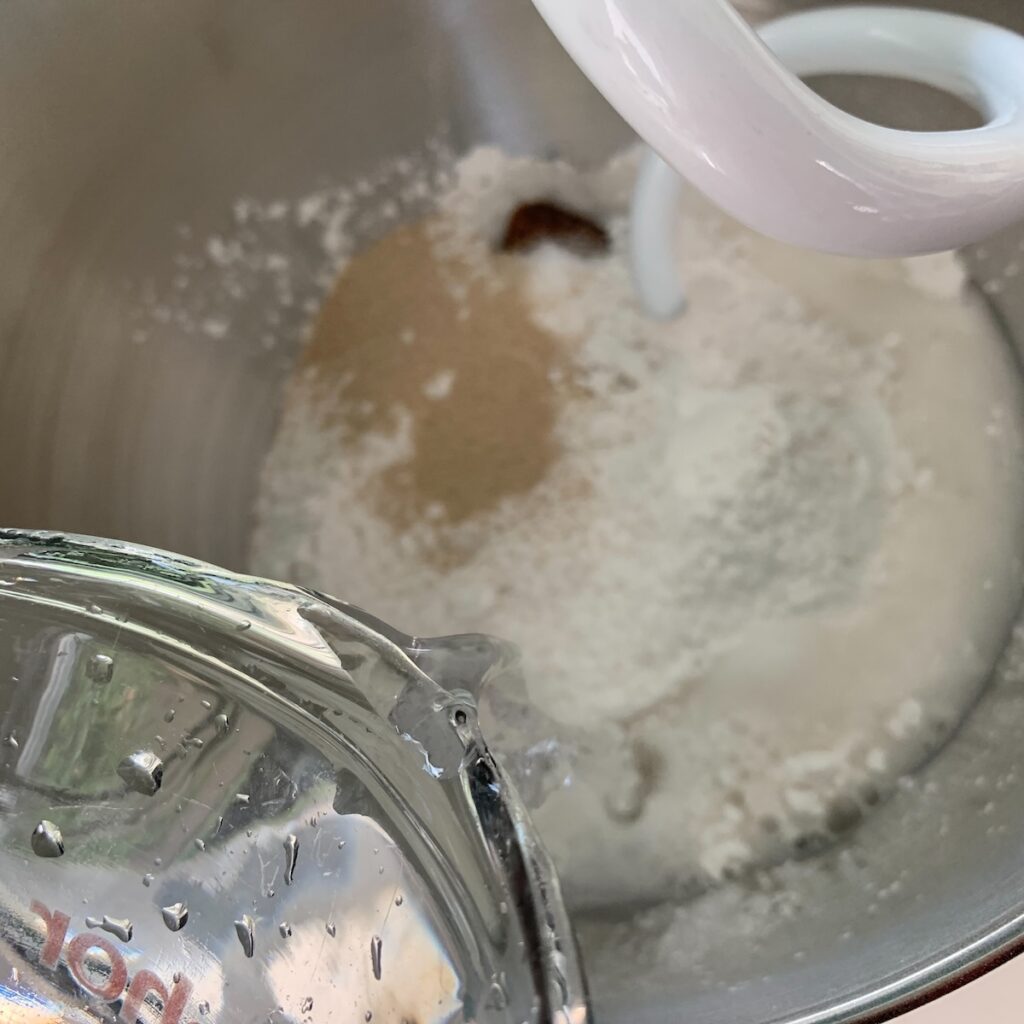 Bird's eye view: water being poured into a mixing bowl with dry ingredients.