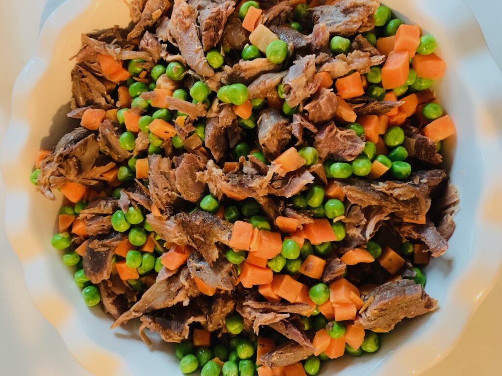 Birds Eye view: shredded lamb, chopped carrots, and peas in a fluted pie dish.
