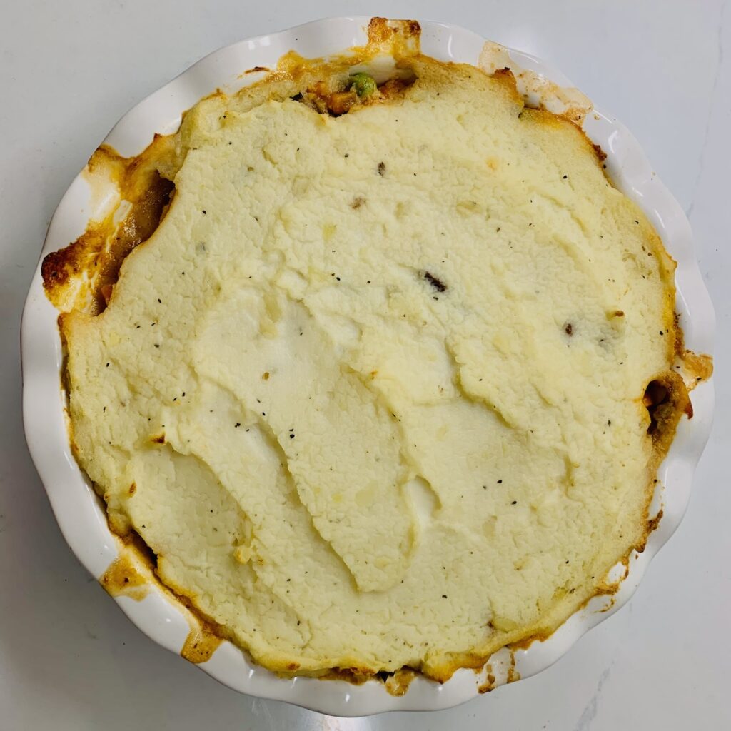 Birds Eye view of baked mashed potato topped shepherd's pie in a round, fluted pie dish.
