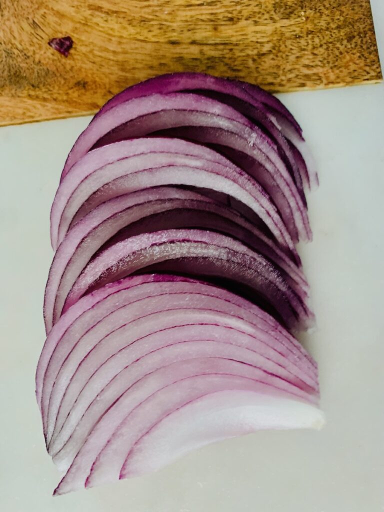 Sliced red onion on a marble/wood cutting board.