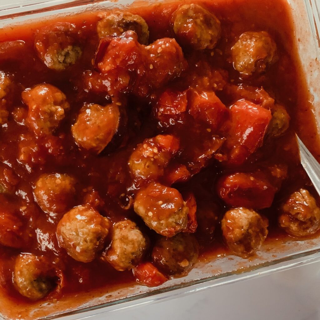 Birds Eye view: square glass container with tomato sauce and meatballs.