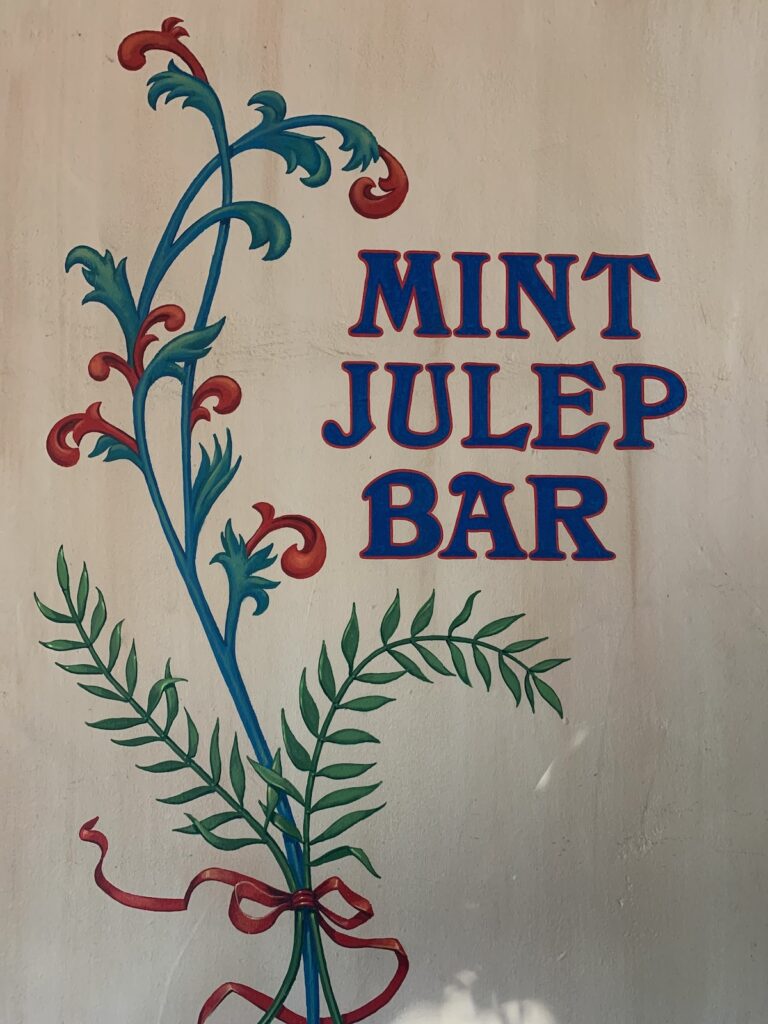 Hand-painted sign with flowers and words "Mint Julep Bar"