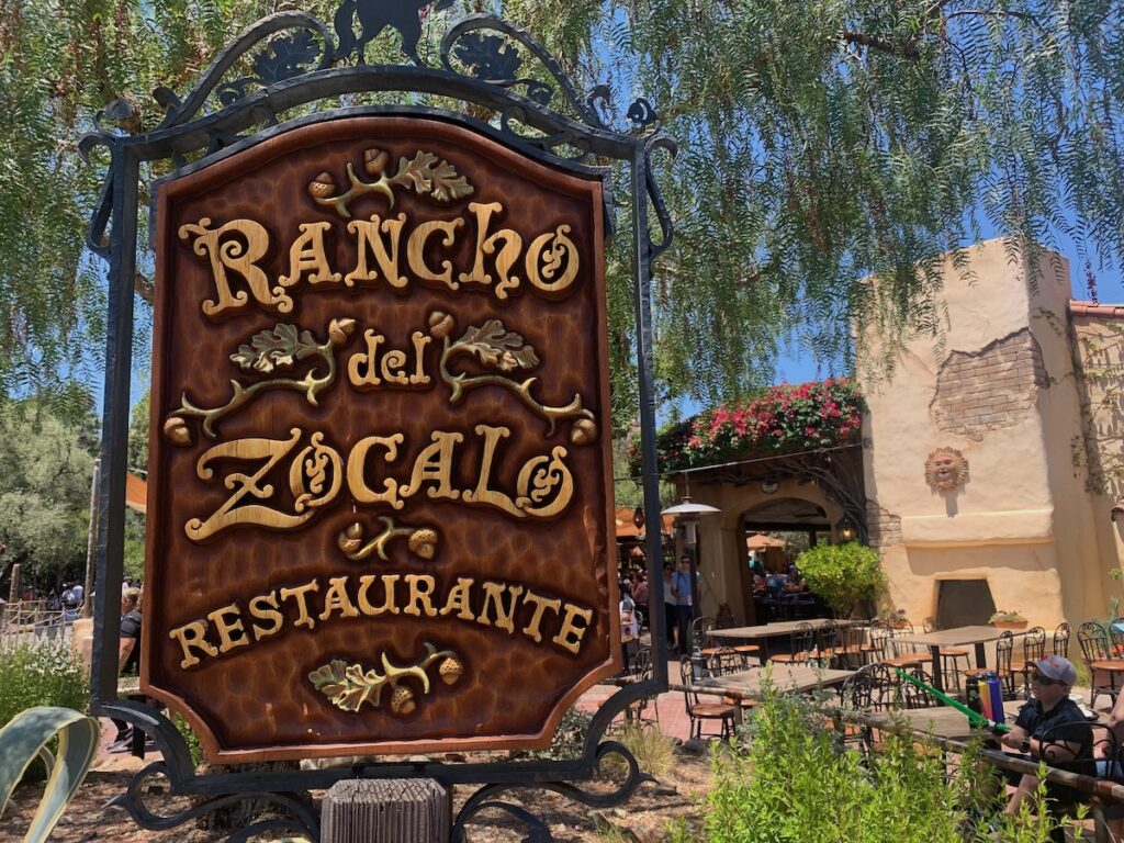 Wooden sign: Rancho del Zocalo Restaurante. Patio in the background.