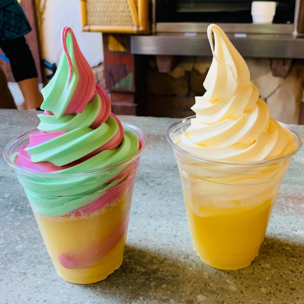 Two dole whip floats on a counter: one is read and green swirl and the other is pale yellow.